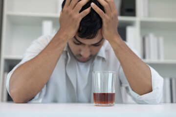 Depressed young Asian man addicted feeling bad drinking whiskey alone at home, stressed frustrated...