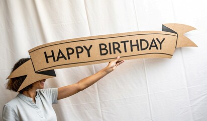 A decorative banner with Happy Birthday written in a bold, stylized font. The banner has a ribbon-like appearance and is set against a vibrant, glowing background with sparkles and a soft gradient of 