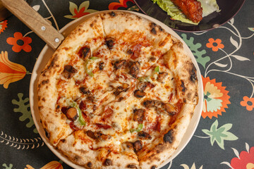 Delicious Italian Pizza with Toppings and a Side of Wings