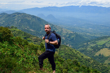 Portrait of a happy and confident adult male hiker with a backpack, smiling at the camera while...