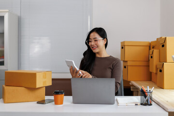 Asian female entrepreneur calculating shipping costs in home office