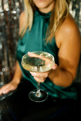 Elegant woman holding a coupe glass with sparkling wine at a party