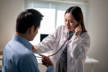woman in a white lab coat is checking a man's heart