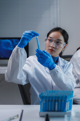 Scientist analyzing blue liquid in test tube in laboratory