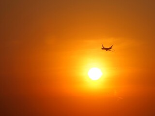 Beautiful aerial view of orange sky and sun at outdoor with blurred background. Landscape panorama photography concept design at airport. Silhouette of airplane at sunset time.