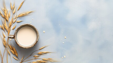 Rustic Ceramic Cup with Oat Milk – Top View on Pastel Blue Surface with Golden Wheat
