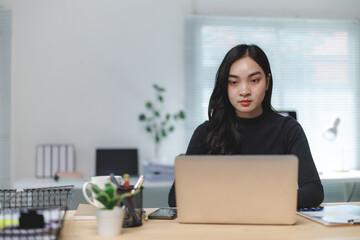 Young asian businesswoman working on laptop in modern office