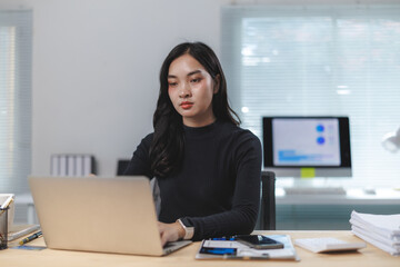Young asian businesswoman working on laptop in modern office