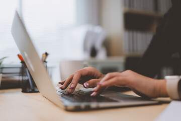 Businesswoman typing on laptop keyboard in modern office, working on computer, business concept