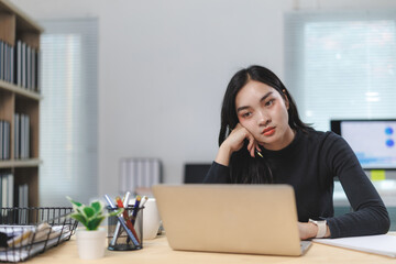 Bored businesswoman resting chin in hand at office desk