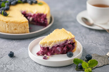 Homemade blueberry or bilberry tart with custard and fresh berries in a plate on the table.
