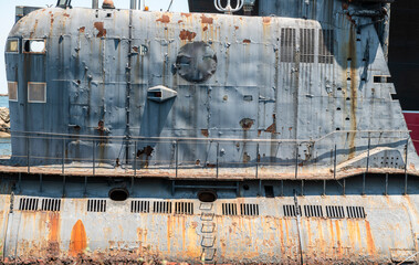 Closeup of the conning tower of an old rusted Russian submarine sitting in a harbor