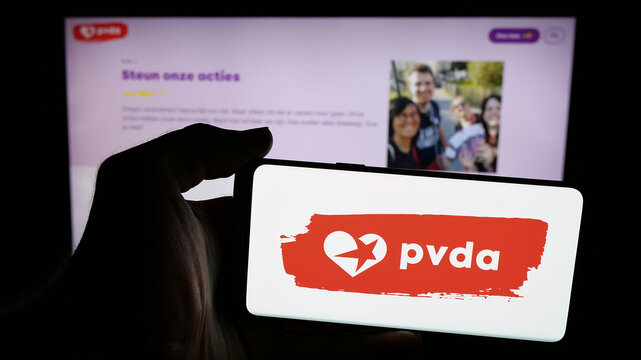 Stuttgart, Germany - 07-10-2025: Person holding mobile phone with logo of Partij van de Arbeid van Belgie (PVDA) on screen in front of web page. Focus on phone display.
