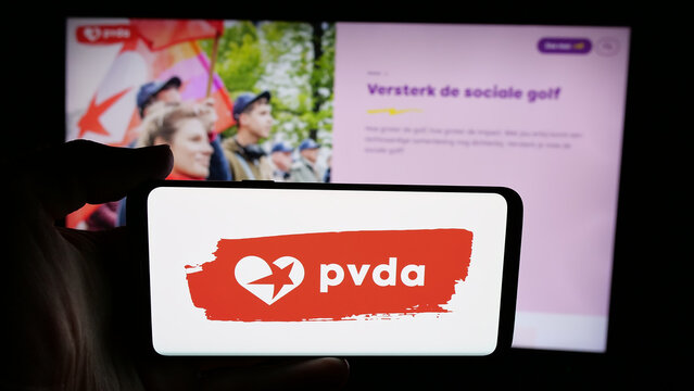 Stuttgart, Germany - 07-10-2025: Person holding cellphone with logo of Partij van de Arbeid van Belgie (PVDA) on screen in front of webpage. Focus on phone display.
