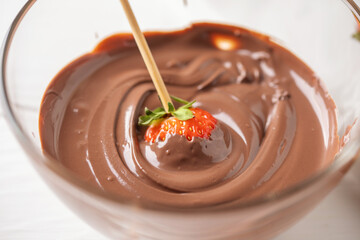 Strawberries dipped in melted chocolate for glazing