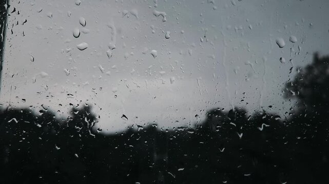 It's raining outside the window, and on the window, raindrops are running down the window