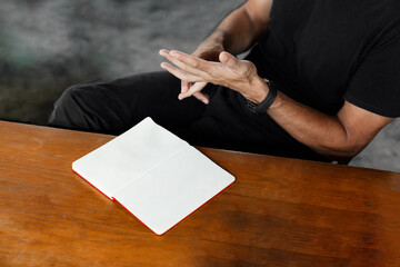 Man Sitting at Desk with Blank Notebook Mockup, Hands in Gesture
