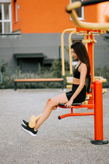 Young woman exercising at outdoor gym in urban setting during sunny day