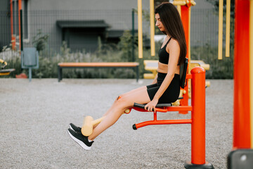 Young woman exercises at outdoor gym using leg press machine in vibrant setting