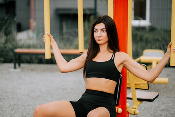 Woman exercises at outdoor gym during daytime in sporty attire for fitness routine