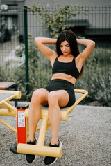 Woman exercising outdoors on fitness equipment in a park during daytime training session