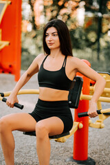 Woman exercising at outdoor gym during sunny day in urban park setting
