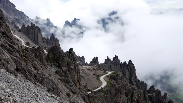 A narrow mountain pass winding through jagged rock cliffs with clouds moving in the background, Panorama of mountain landscape with clouds in the morning sky, high-quality cinematic horizontal video