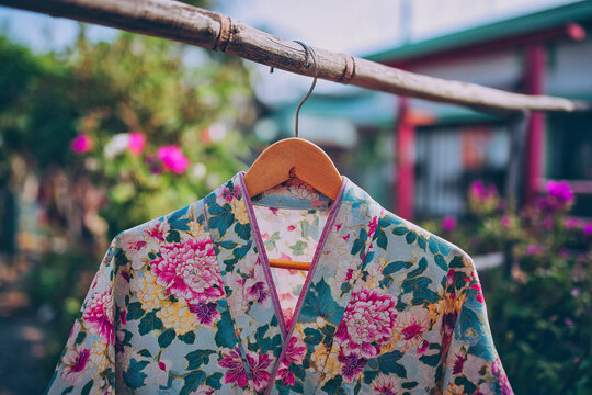 Colorful floral yukata on wooden hanger drying on bamboo pole in traditional Japanese summer garden