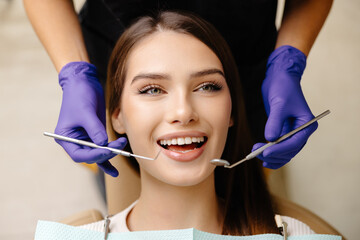 Happy patient during a visit to the dentist. The doctor is checking teeth using a dental instrument, ensuring proper oral care in the dentistry clinic