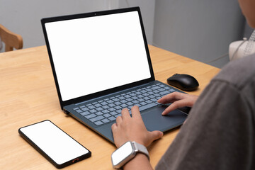 Person typing on laptop with blank screen at desk, smartphone and smartwatch, technology and workspace concept