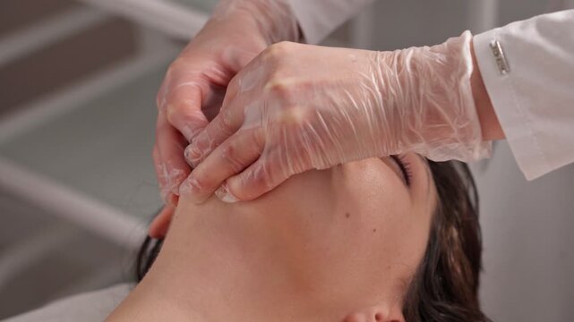 cosmetologist makes a buccal massage of the patient's facial muscles.