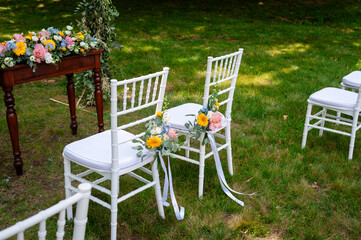 Outdoor wedding chairs on green lawn with floral decorations