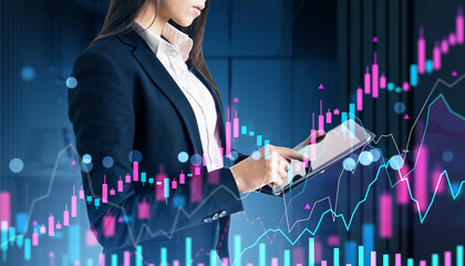 Businesswoman analyzing financial graphs on tablet with digital stock market data overlay in a corporate office at night conceptually displayed.
