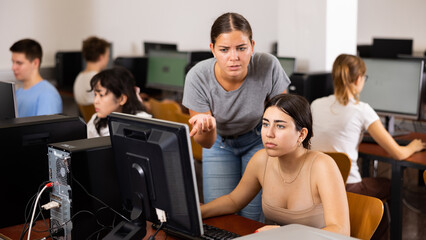 Fototapeta premium Young woman teacher and teenage girl studying computer science in classroom in school.