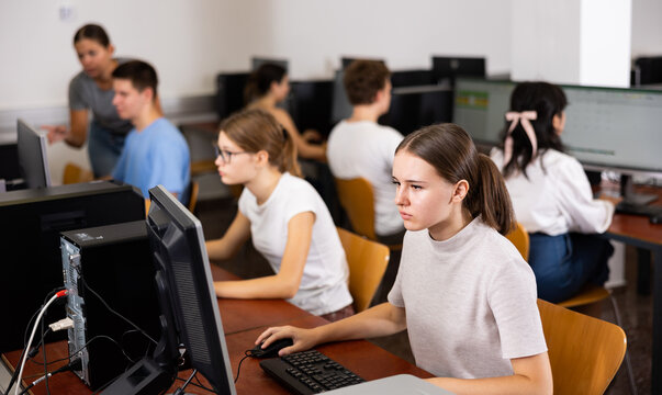 Portrait of interested teen girl during lesson in computer room of school computer class