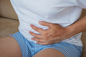 The person clutching their abdomen signals acute gastrointestinal discomfort, possibly due to...