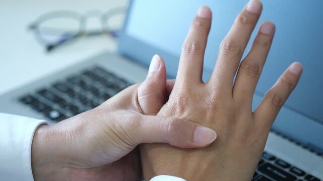 After prolonged computer use, hand discomfort arises from repetitive strain, suggesting muscle fatigue or possible nerve compression in a work setting. Slow motion VDO of healthcare & medical concept.