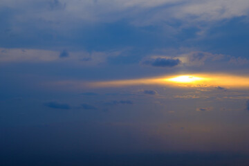 orange sun light behind blue rainy clouds in the sky