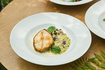 Cod steak with creamy ptitim, bright natural lighting, overhead minimal composition
