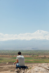 man sitting on a hill and looking mount