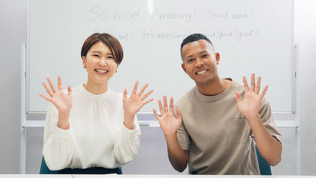 教室で手を振る黒人男性と日本人女性