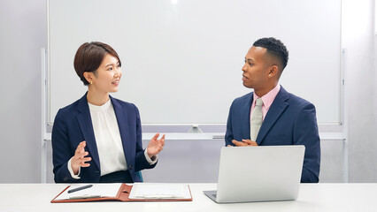 A Japanese female staff member interviewing a black male businessman