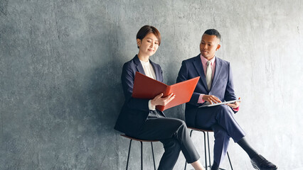 A black male businessman and a Japanese female staff member having a conversation in a stylish room