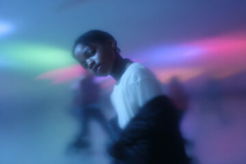 Fototapeta premium dynamic portrait captured at roller rink showcasing individual gliding on skates amidst vibrant lights and colors