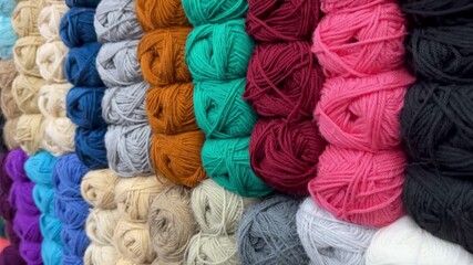 a vibrant and neatly organized collection of multicolored wool yarn balls on display at a local market. - Powered by Adobe