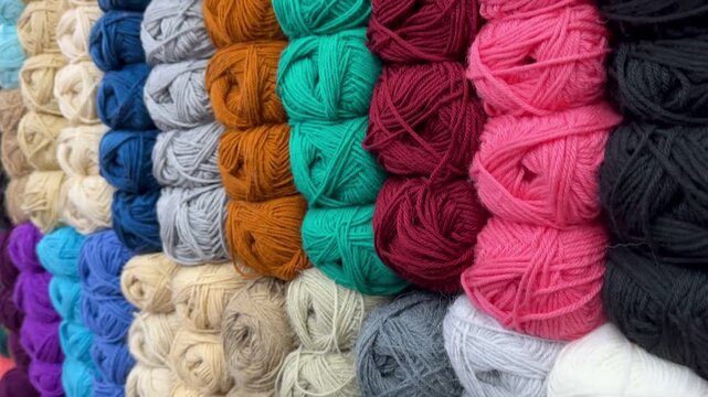 a vibrant and neatly organized collection of multicolored wool yarn balls on display at a local market.