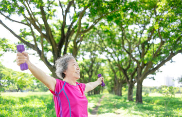 Happy Asian senior woman lifting dumbbell