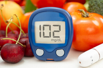 Asian hand holding digital glucose monitor measure with vegetable and fruit healthy food.