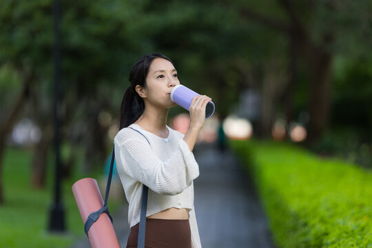 Sport woman drinking water after yoga exercise at park