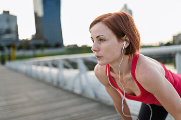 Female runner resting and catching breath, bent over after morning run.